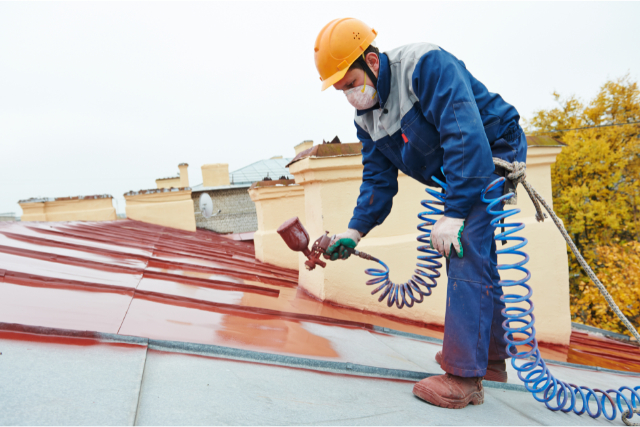 Exterior Painter painting a roof with spray gun