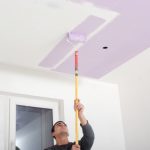 House Painter with roller painting a ceiling purple