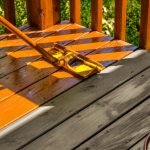 Staining wooden deck of a backyard deck with stainer